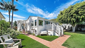 A white two-story house with a covered porch and a brick pathway.