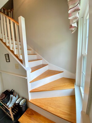 Eine Treppe mit weißen Geländern und Holzstufen, die zu einer Empore führen.