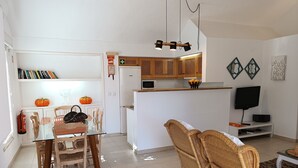 Ett modernt vardagsrum med matplats, kök och tv.