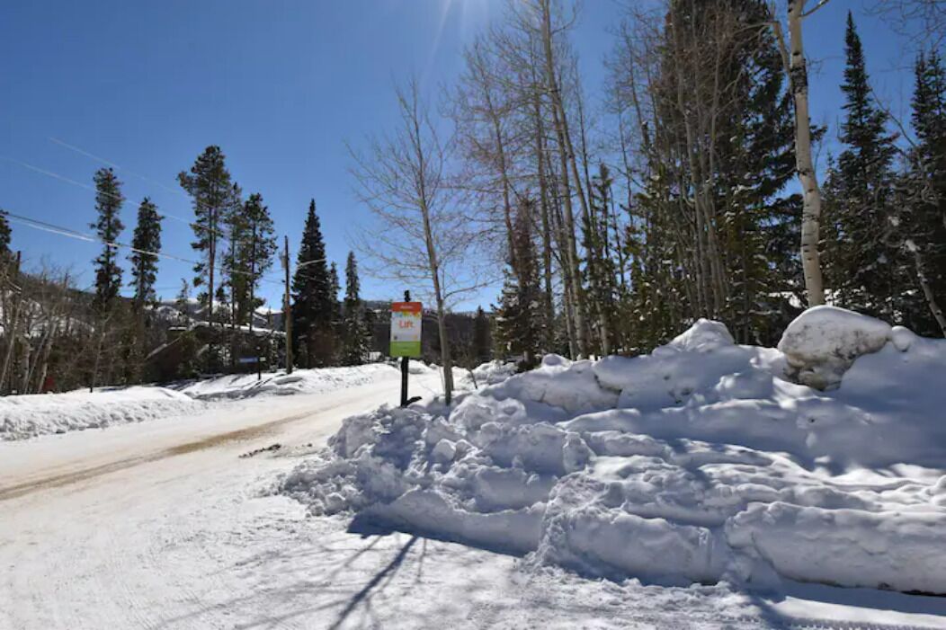 Un camino cubierto de nieve con un cartel y árboles al fondo.