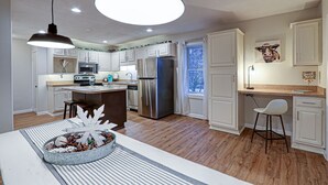 A modern kitchen with white cabinetry, stainless steel appliances, and a central island.