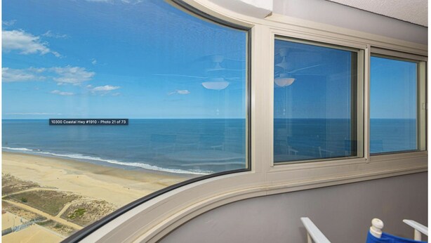 Een kamer met een groot raam met uitzicht op zee en strand.
