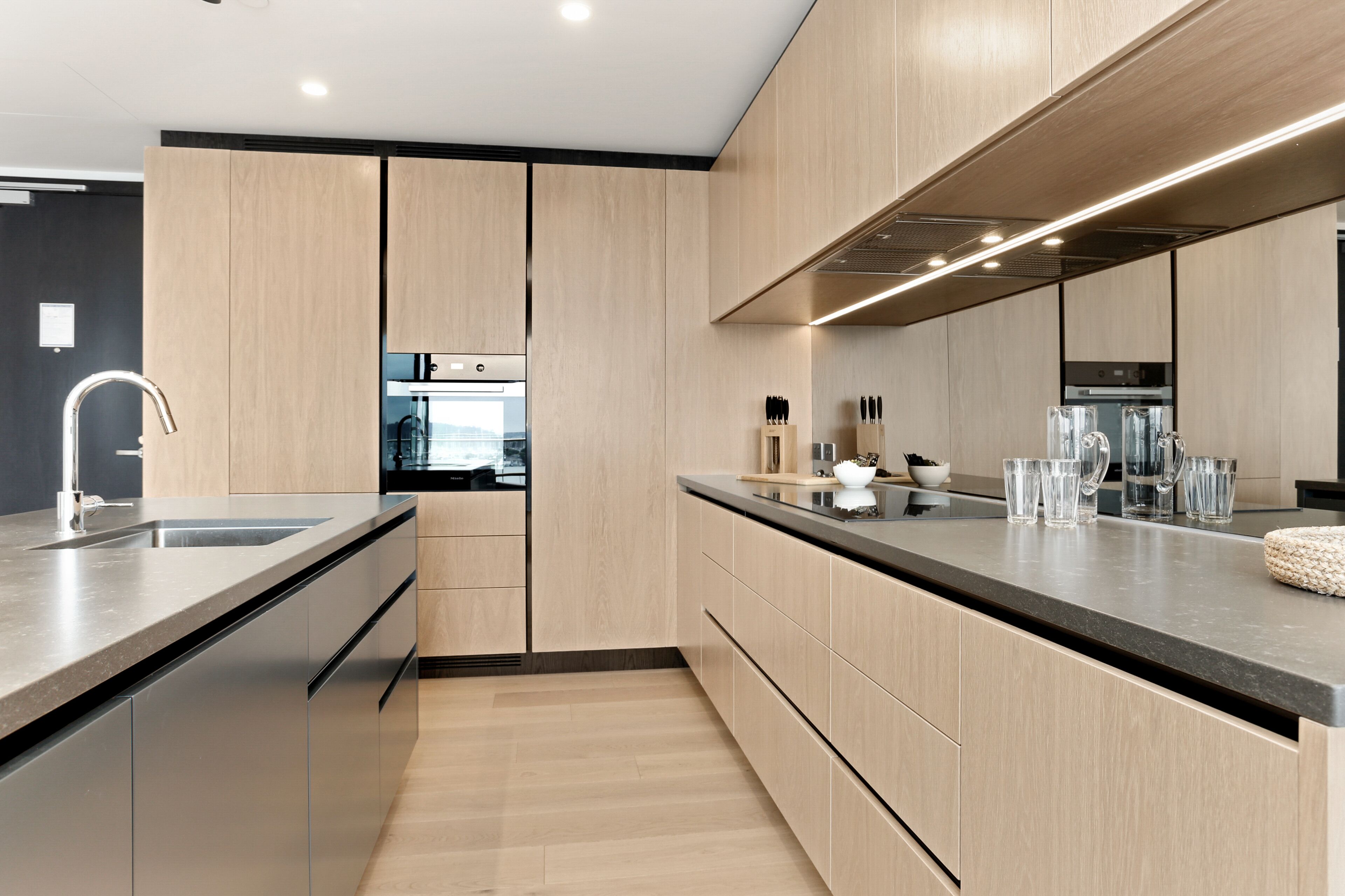 A modern kitchen with wooden cabinets, a stainless steel sink, and a black countertop.