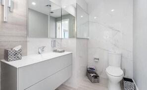 A modern bathroom with a white vanity, a large mirror, and a toilet.