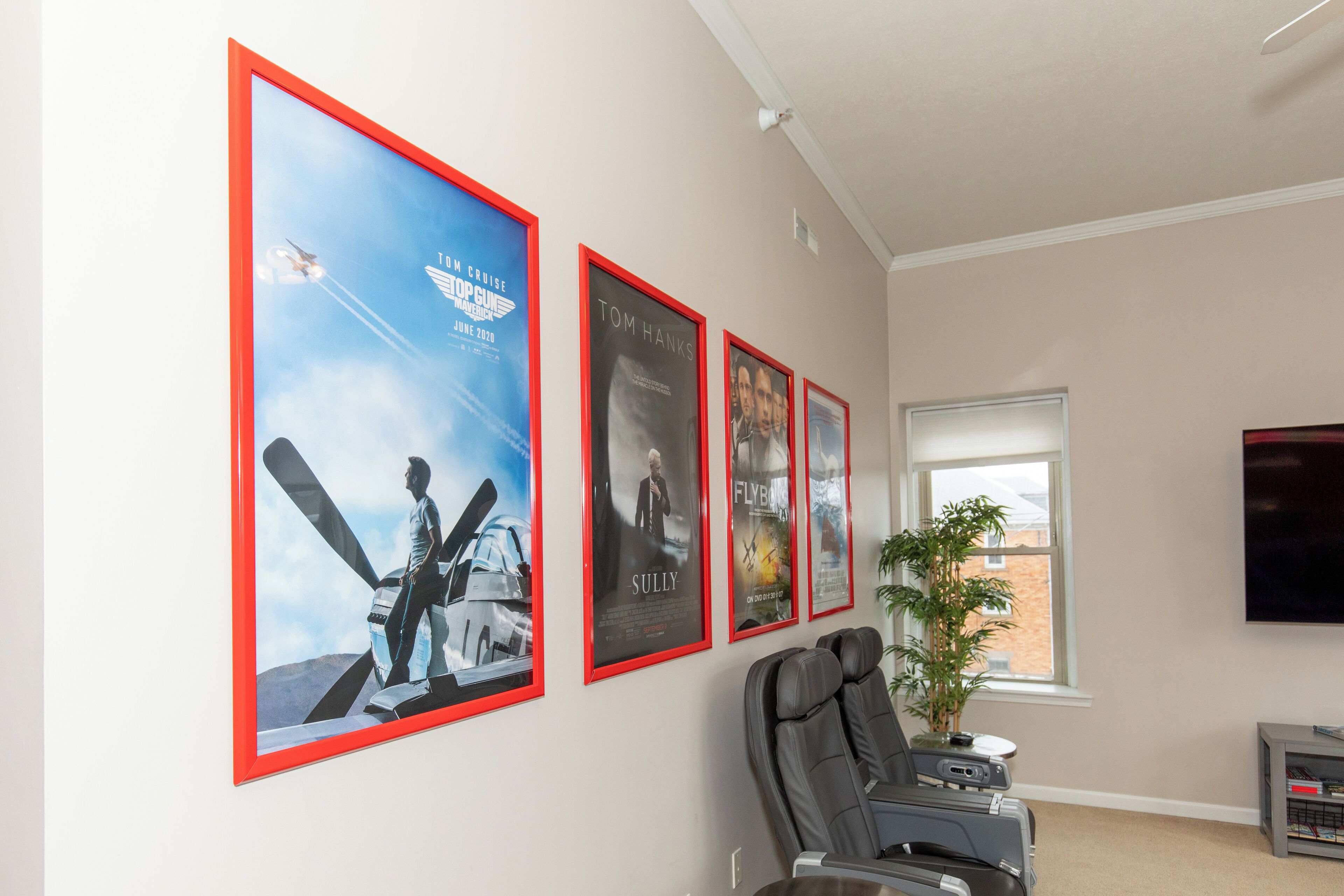 Un salon équipé d’un fauteuil massant, d’un grand téléviseur et de plusieurs affiches de films accrochées au mur.