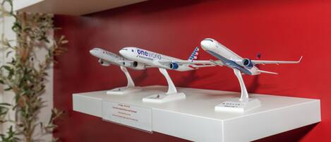 Una exhibición de modelos de aviones sobre un estante blanco frente a una pared roja.