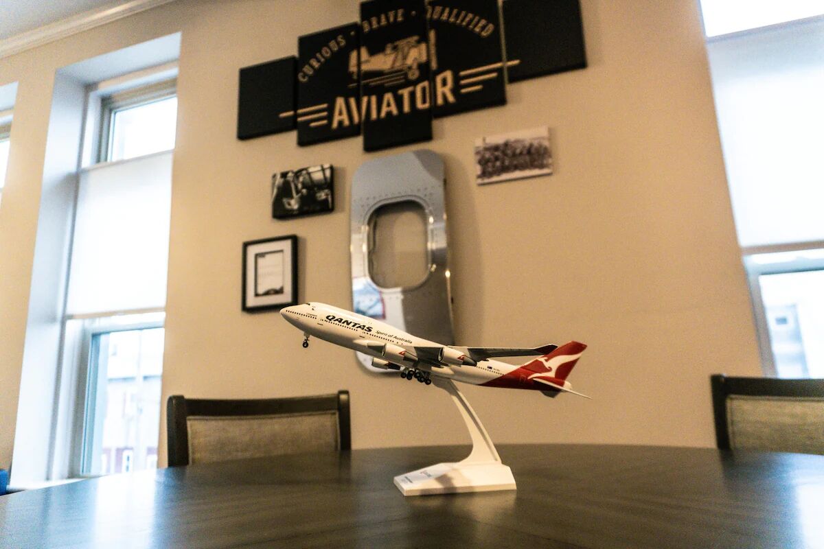 Un modelo de avión sobre una mesa en una habitación con ventana y decoración de temática aeronáutica.