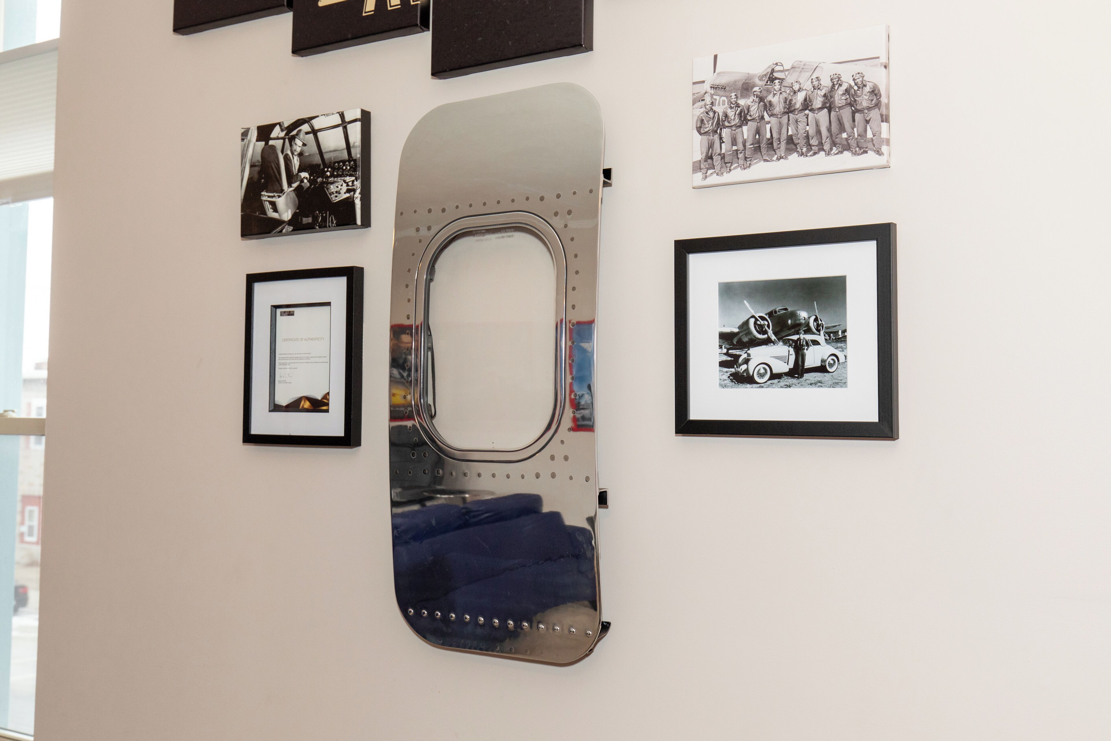A wall with framed photographs and a large mirror.