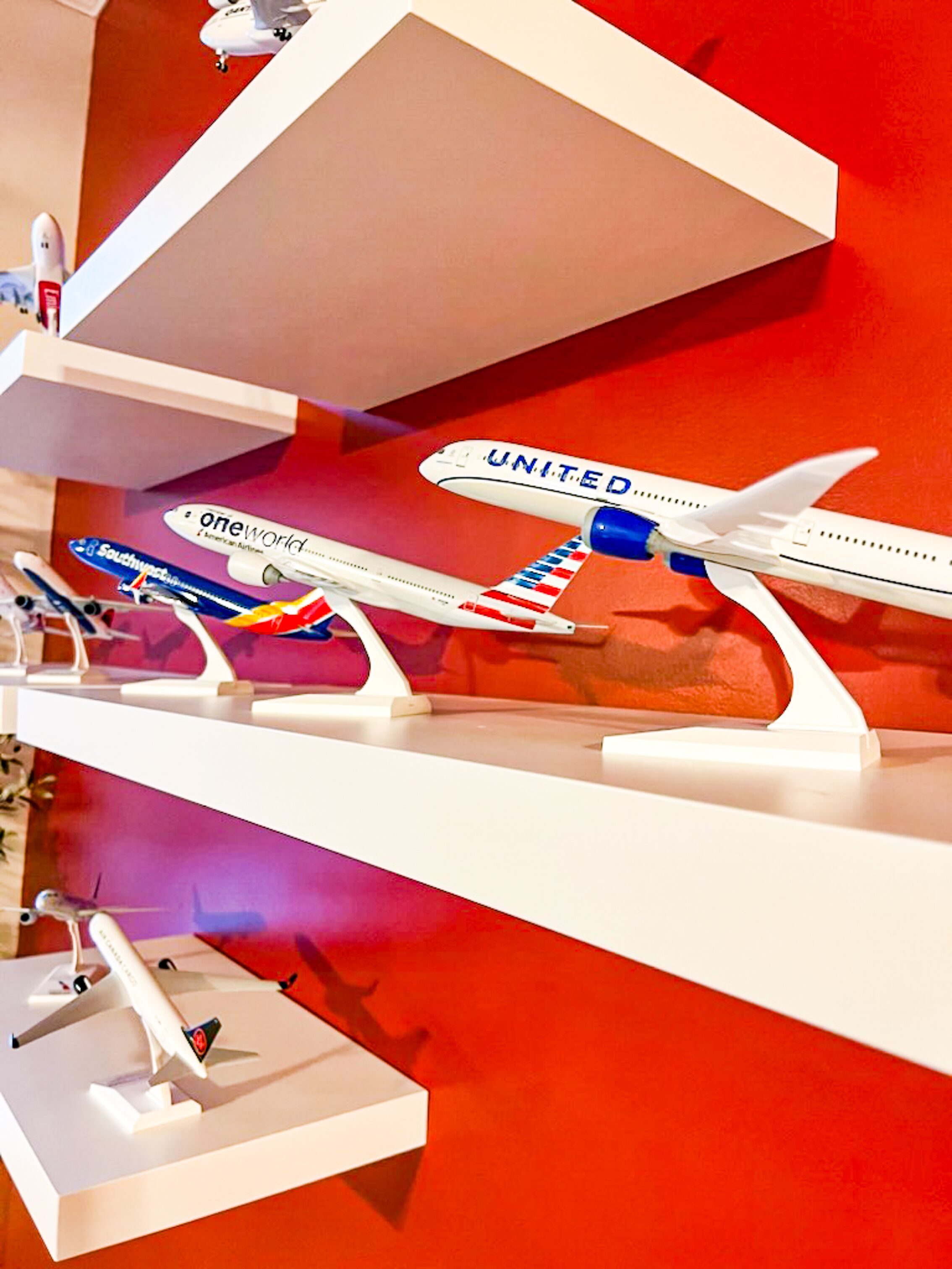 A model display of various airplanes on white stands against a red background.