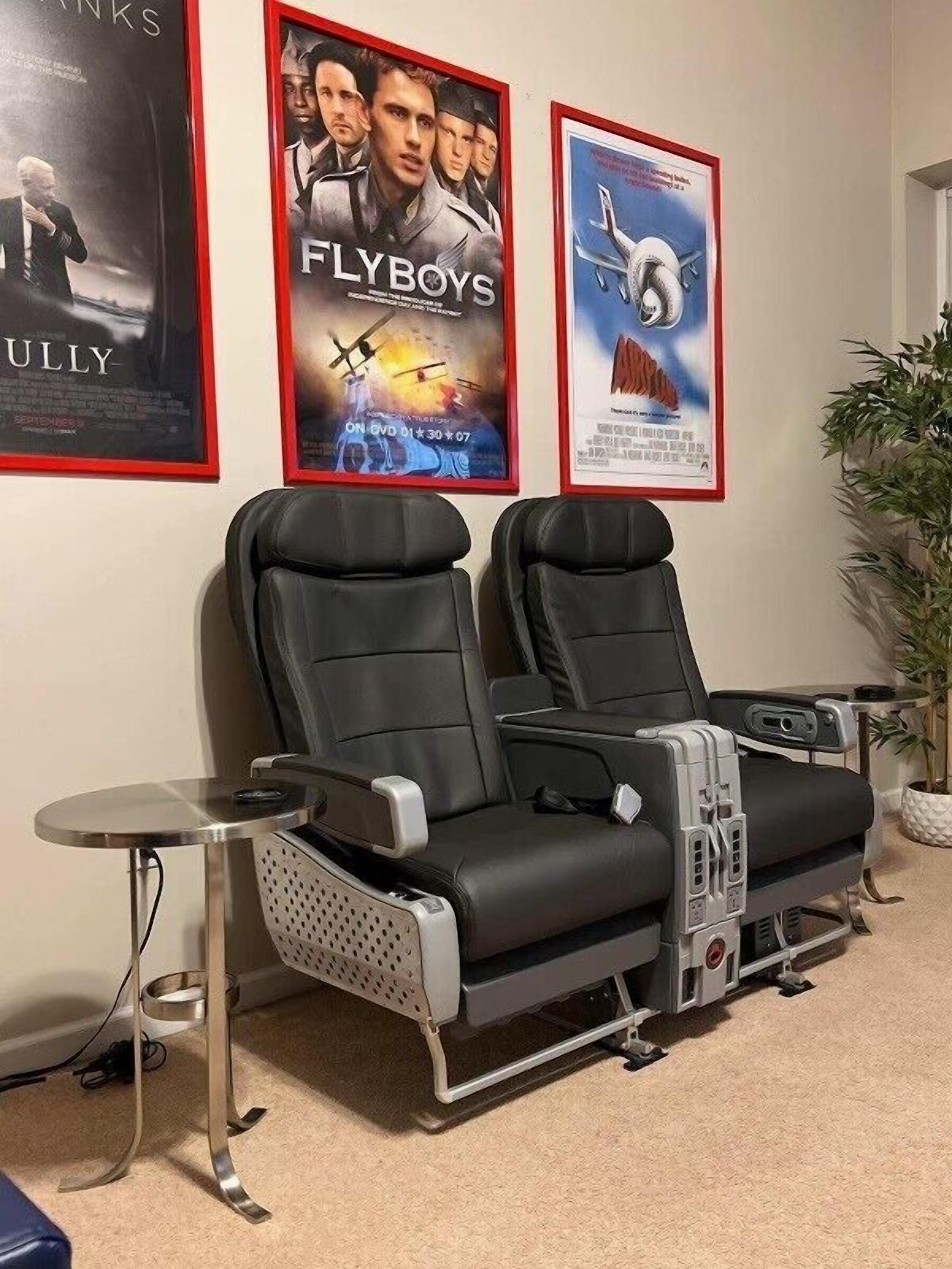 Une pièce avec deux fauteuils inclinables, une petite table et des affiches au mur.