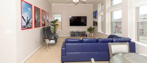 A living room with a blue sofa, a TV, and a ceiling fan.