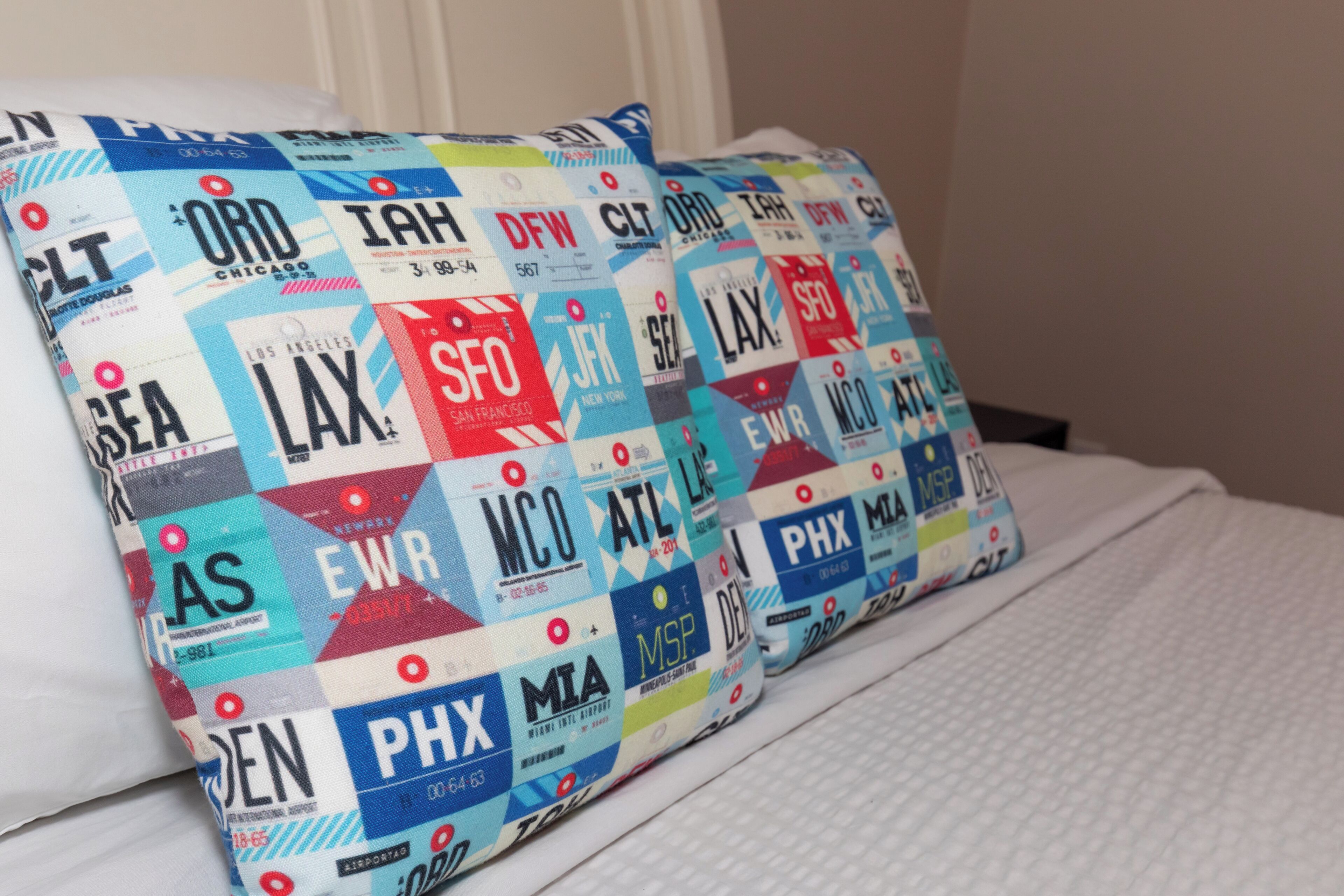 Ein Bett mit Kissen, verziert mit Flughafencodes und Städtenamen.