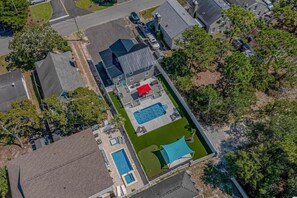 Vue aérienne d’une propriété résidentielle dotée d’une piscine, d’un court de tennis et d’un patio couvert.