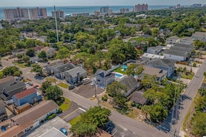Vue aérienne d’un quartier résidentiel avec des maisons, des rues et une grande étendue d’eau en arrière-plan.