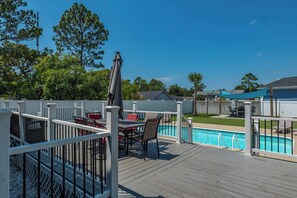 A wooden deck with a pool, white fence, and outdoor furniture. - The Seven Oh Five | Coastal Duplex (North Myrtle Beach)