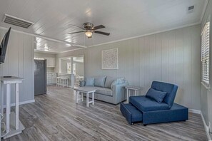 A spacious living area with a sofa, a coffee table, and a TV on a stand.