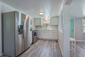 A compact kitchen with a stainless steel refrigerator, a built-in oven, and white cabinetry.