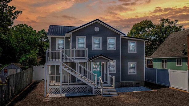 A two-story house with a front porch, a staircase, and a small deck.