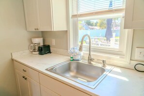 A kitchen with a sink, a coffee maker, a toaster, and a window with blinds.