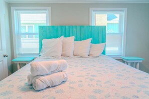 A bedroom with a bed, pillows, a folded towel, and two nightstands.