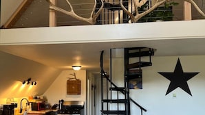 A loft-style kitchen with a wooden dining area, a spiral staircase, and a star decoration on the wall. - HOT TUB ~ 31 Acres ~Bring ATVs/Border Nat'l Forest (Teller County)