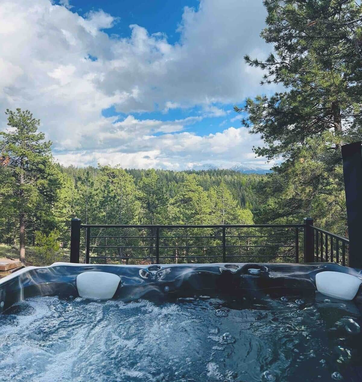 A hot tub with a view of a forest and mountains.