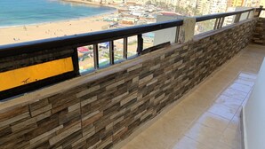 Un balcón con muro de piedra y vista a la playa y al paisaje urbano.