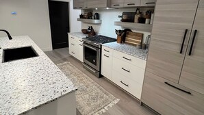 Una cocina moderna con armarios blancos, encimera de granito y horno empotrado.