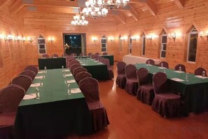Un salón de conferencias con largas mesas y sillas, paredes de madera y candelabros.