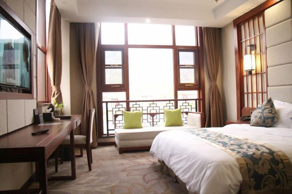 A hotel room with a bed, a desk, and a TV.