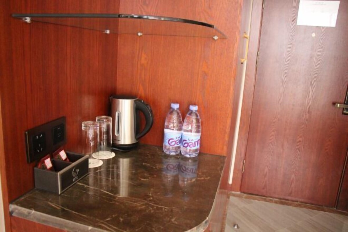 A small kitchenette area with a coffee maker, two bottles of water, and a glass container on a marble countertop.