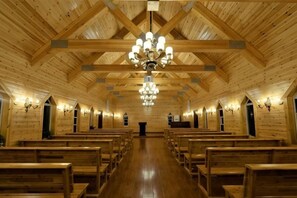 A wooden interior with a high ceiling, chandeliers, and rows of wooden benches. - Yingzhigu Holiday Hotel (Mengyin)