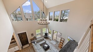 A spacious living area with a large window, a chandelier, and a view of the outdoors. - Miller's Cove on Lake Texoma! Luxury Lakeview Home! (Pottsboro)