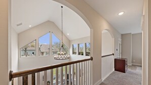A spacious interior with a high ceiling, large windows, and a wooden railing. - Miller's Cove on Lake Texoma! Luxury Lakeview Home! (Pottsboro)