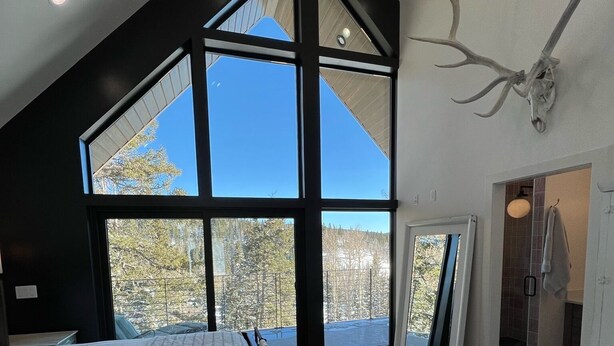 A bedroom with a large skylight, a bed, a cowhide rug, and a mounted deer skull.