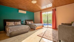 A bedroom with two beds, a sofa, and a large window with curtains. - The Lake Village, La Fortuna de San Carlos (La fortuna)