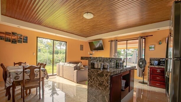 A spacious kitchen with a marble island, wooden ceiling, and a dining area with a table and chairs. - The Lake Village, La Fortuna de San Carlos (La fortuna)