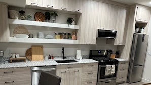 A modern kitchen with light wood cabinets, stainless steel appliances, and a granite countertop. - Steps away from the slopes!  Recently built Scandinavian Cabin with Jacuzzi! (Beaver)
