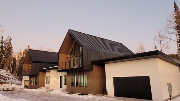 A modern residential building with a sloped roof, large windows, and a garage. - Steps away from the slopes!  Recently built Scandinavian Cabin with Jacuzzi! (Beaver)