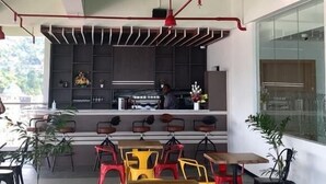 A modern cafe with a green ceiling, red pendant lights, and colorful chairs. - MaxOneHotels.com at Jayapura (Jayapura)