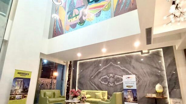 A spacious lobby with a high ceiling, a large mural, a seating area with sofas, and a marble floor. - MaxOneHotels.com at Jayapura (Jayapura)