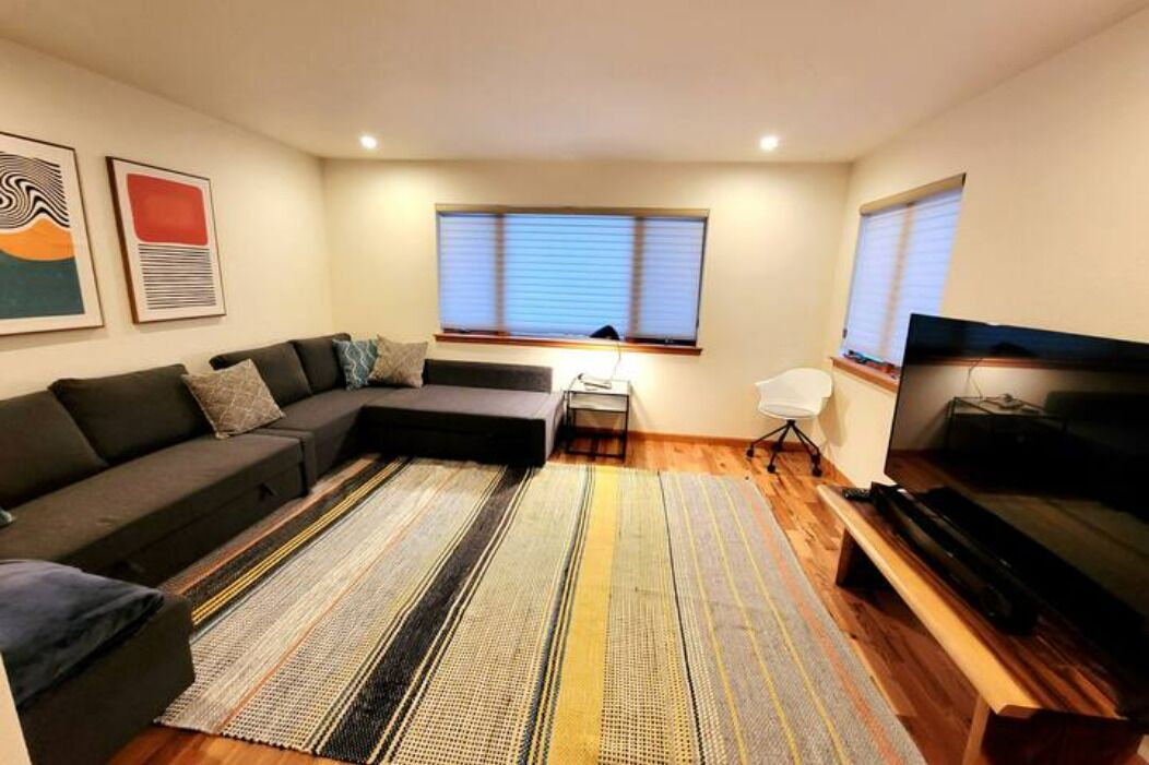 Una sala de estar moderna con un sofá modular, un televisor de pantalla plana y una alfombra a rayas.