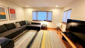 Una sala de estar moderna con un sofá modular, un televisor de pantalla plana y una alfombra a rayas.