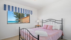 A bedroom with a bed, a window with a view of the sea, a lamp, and a small table. - Gorgeous Beach and Ocean Views - Located right on the Beach and Pet Friendly! (Moana)