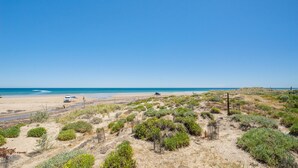 A beach with sparse vegetation and a clear blue sky. - Gorgeous Beach and Ocean Views - Located right on the Beach and Pet Friendly! (Moana)