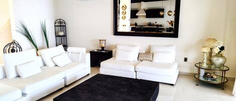 Una sala de estar moderna con un sofá blanco, un tapete negro y un espejo decorativo.