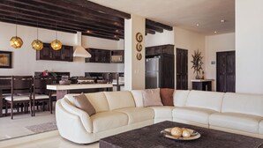 Een moderne woonkamer met een hoekbank, een salontafel en een keuken op de achtergrond.