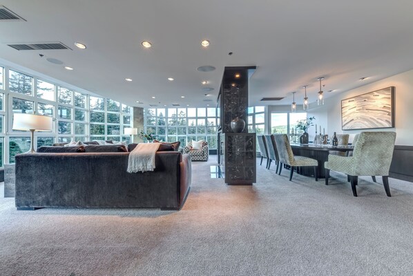 A spacious living area with a large sofa, a dining table with chairs, and a fireplace.