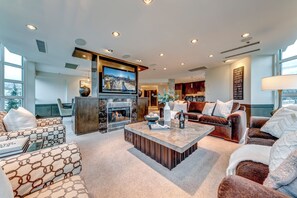 A spacious living room with a fireplace, comfortable seating, and a large TV.