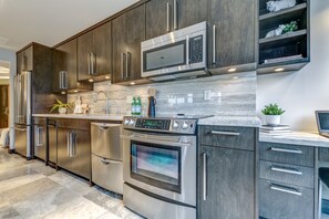 Une cuisine moderne dotée d’appareils électroménagers en acier inoxydable, d’armoires en bois foncé et d’un plan de travail en marbre.